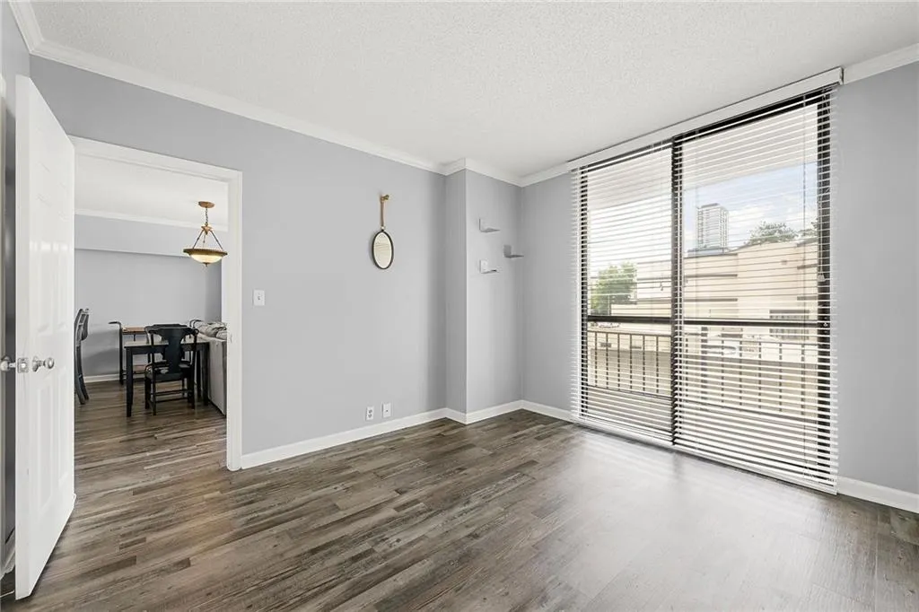 Unfurnished room featuring crown molding, dark wood finished floors, and a textured ceiling