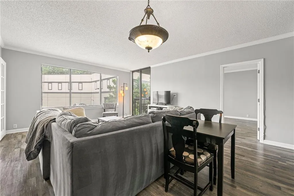 Living room featuring a textured ceiling, crown molding, and dark wood-style flooring