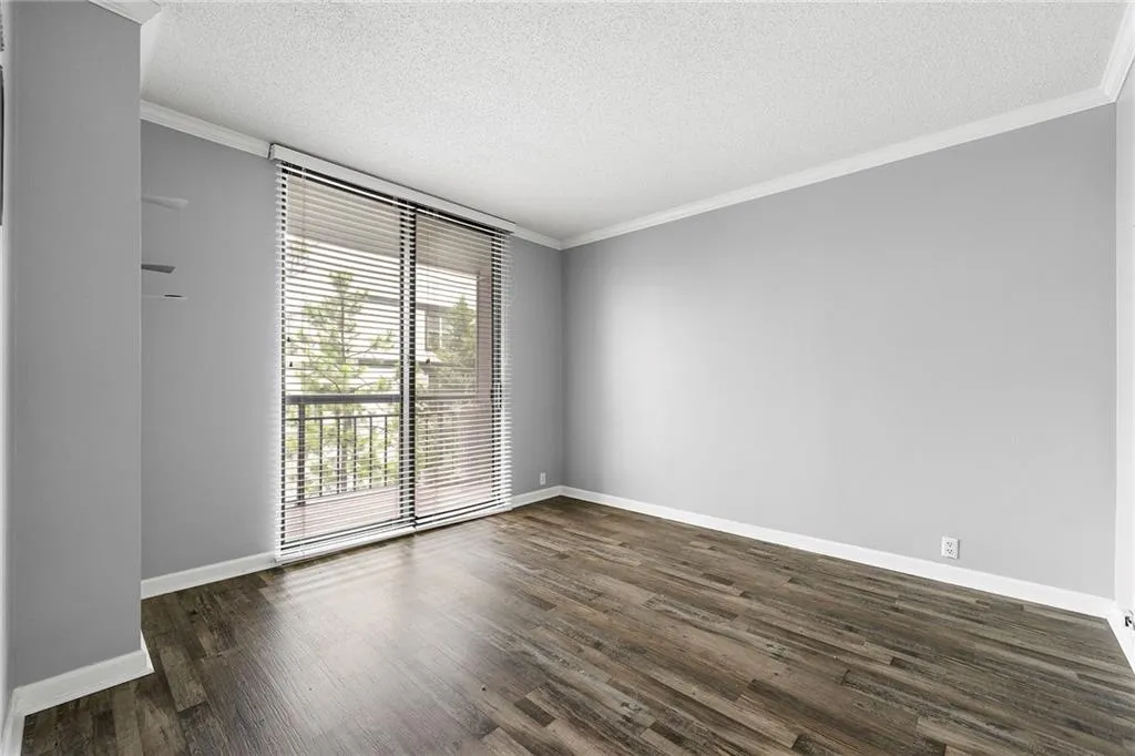 Unfurnished room featuring dark wood-type flooring, ornamental molding, and a textured ceiling
