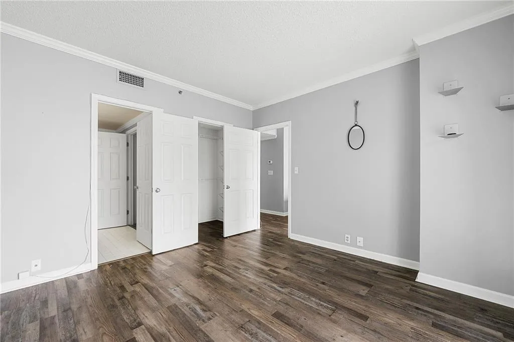 Unfurnished bedroom with dark wood finished floors, crown molding, a textured ceiling, and a closet