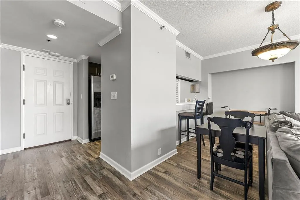 Dining area with ornamental molding, dark wood-style flooring, and a textured ceiling