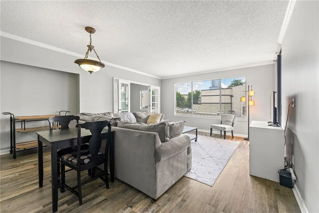 Living area with a textured ceiling, wood finished floors, and crown molding