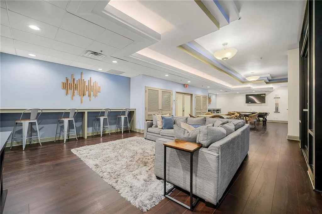 Living room with dark wood finished floors, a tray ceiling, and recessed lighting