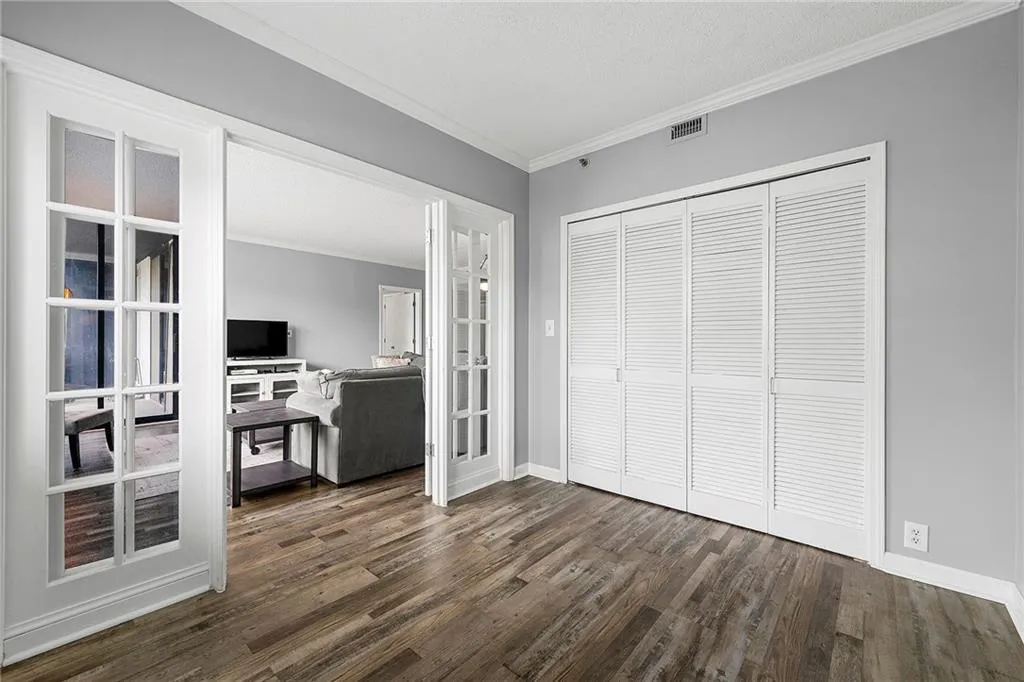 Living area with ornamental molding, dark wood-style flooring, and french doors