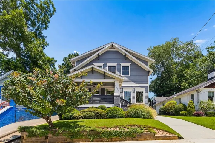 Craftsman-style home featuring a covered front porch, a well-maintained lawn, and mature landscaping