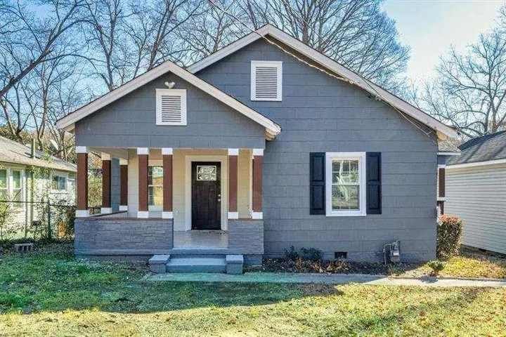Charming cottage-style home featuring a welcoming front porch with tapered columns, blue-painted steps, and a gabled roofline