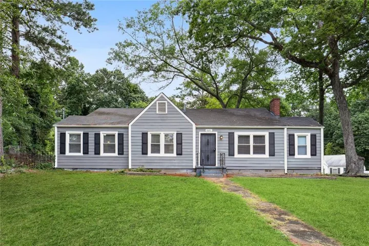 Gray siding exterior with contrasting black shutters, a gabled roofline, and a brick chimney