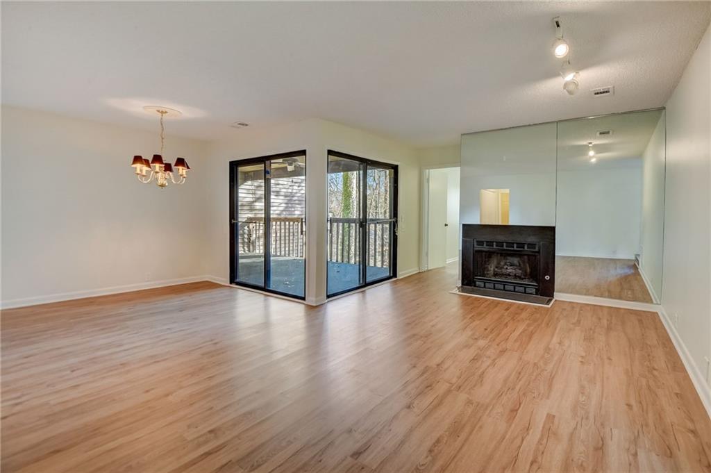Unfurnished living room with an inviting chandelier, light hardwood / wood-style floors, and track lighting