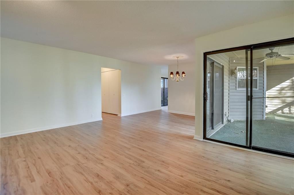 Spare room featuring ceiling fan with notable chandelier and light hardwood / wood-style flooring