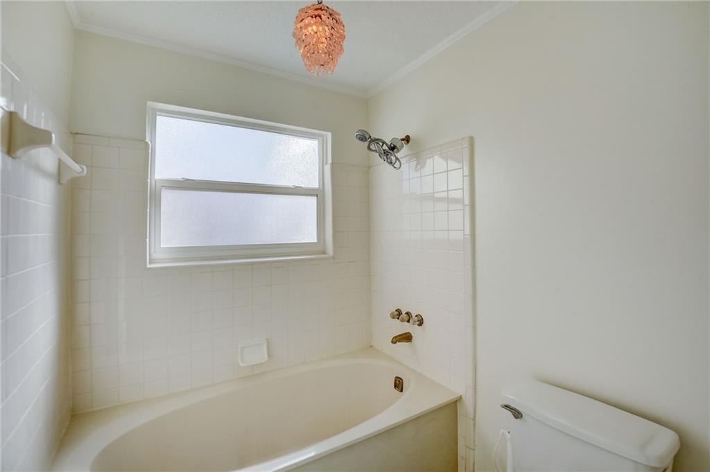 Bathroom featuring crown molding, tiled shower / bath combo, toilet, and plenty of natural light