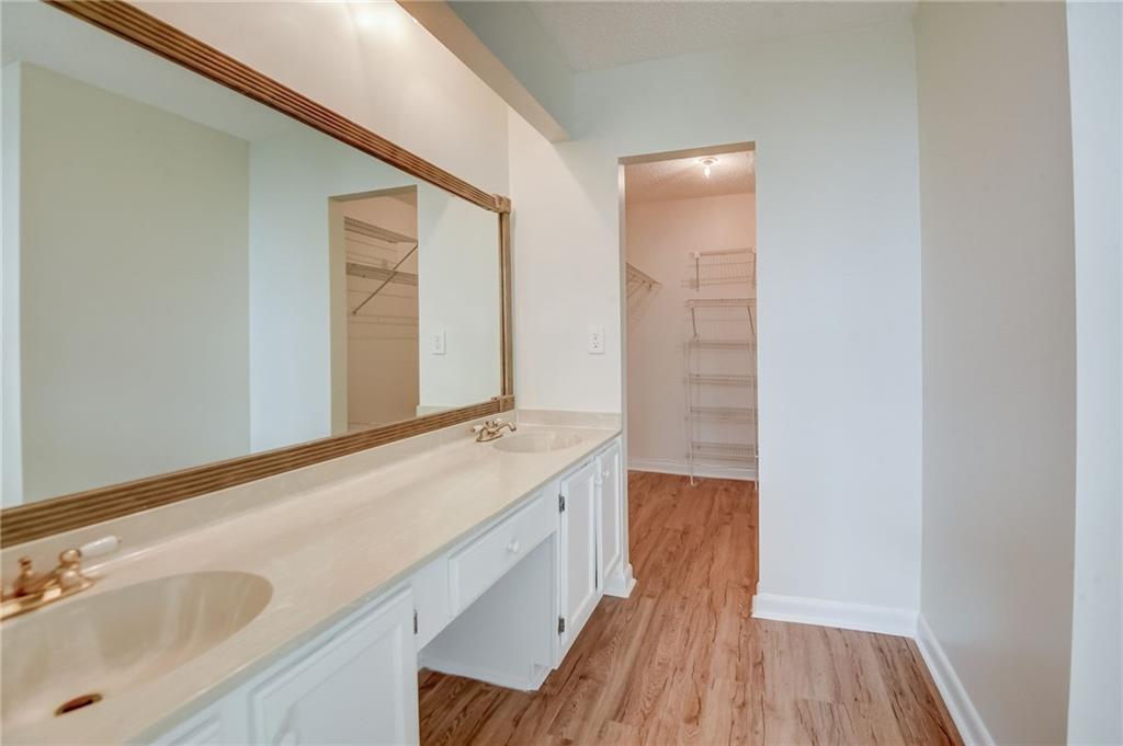 Bathroom featuring hardwood / wood-style floors, vanity with extensive cabinet space, and dual sinks