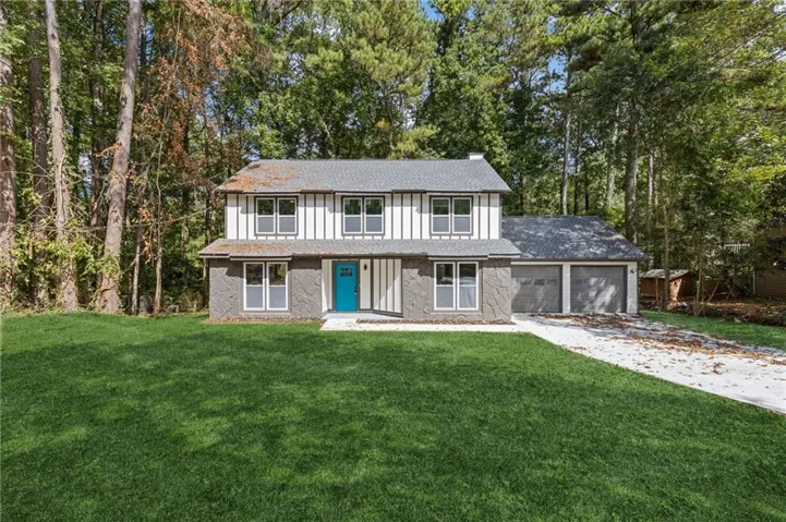 Two-story residence featuring a two-car garage, white siding, stone veneer accents, and a vibrant blue entry door