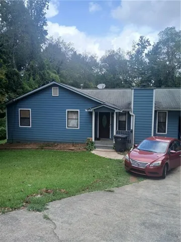 Blue siding exterior with white window trim and a partial concrete driveway