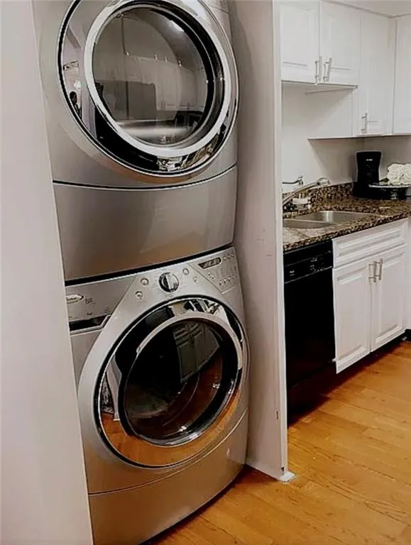 Laundry room featuring stacked washer / drying machine and light wood-style floors