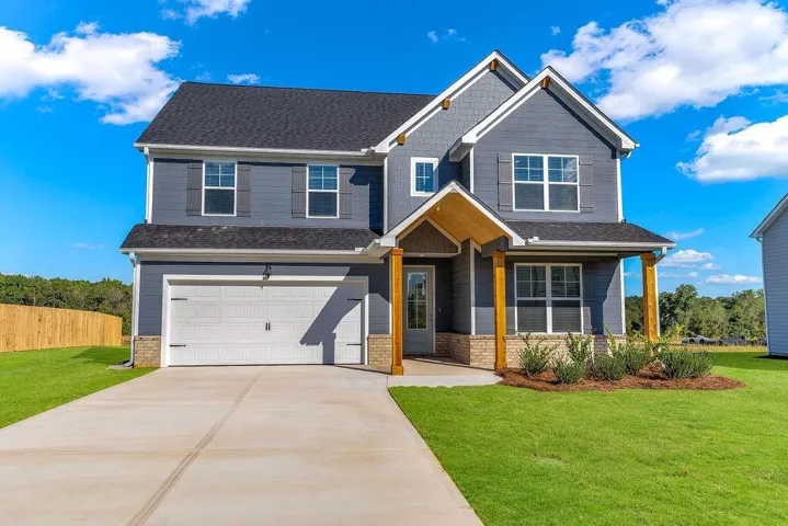 Two-story residence featuring a covered entry porch with wood columns, a two-car garage, and partial brick siding