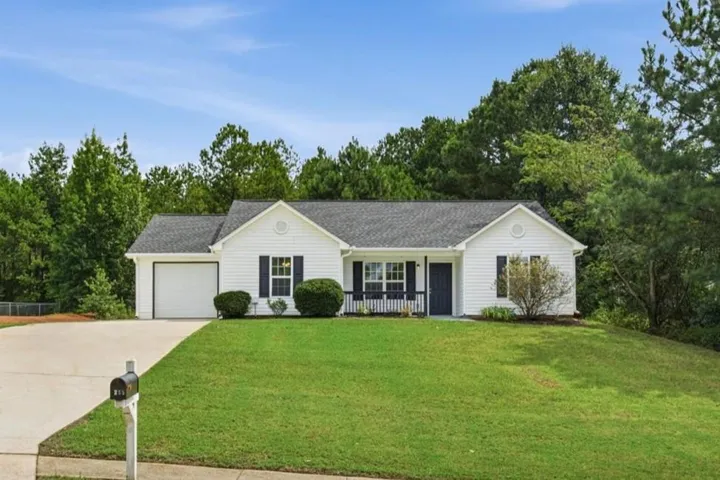 White siding exterior with dark shutters, attached garage, and a covered front entry