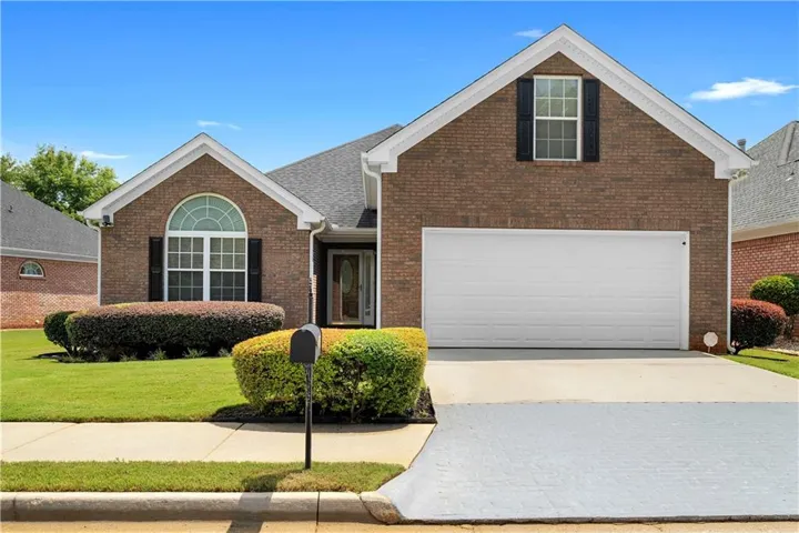 Brick exterior with a gabled roofline, arched window, and attached garage