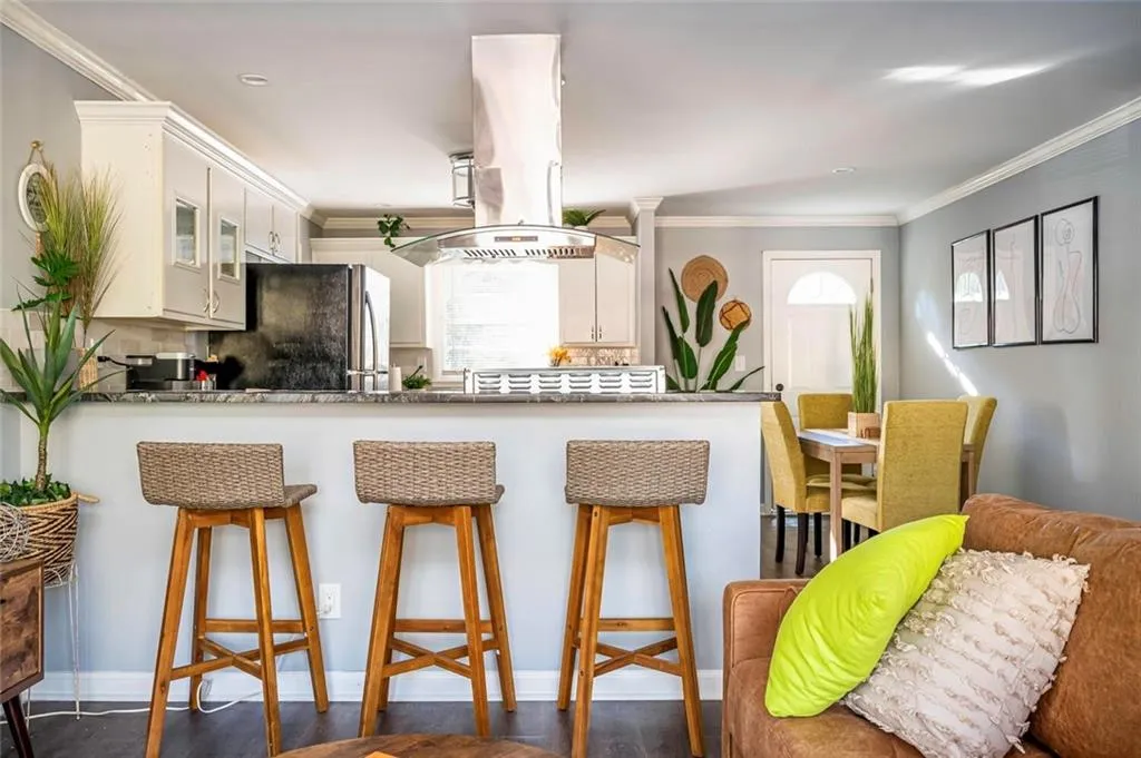 Kitchen featuring ornamental molding, a kitchen bar, island range hood, a peninsula, and tasteful backsplash