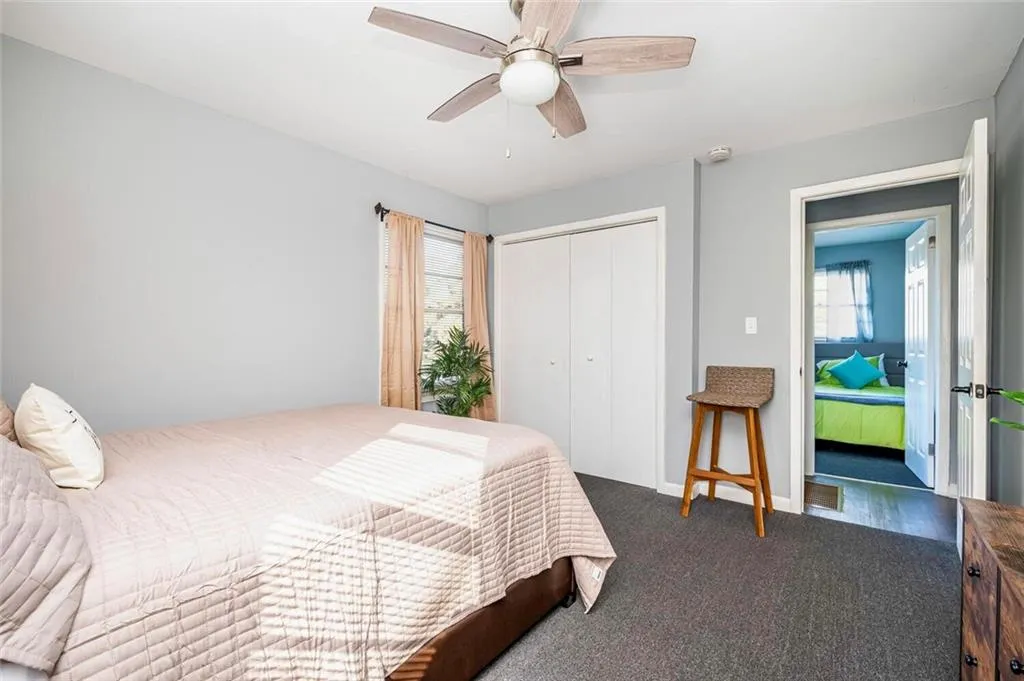Bedroom with dark carpet, a closet, and a ceiling fan
