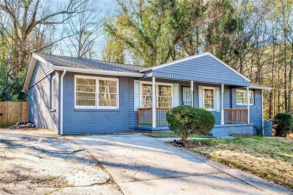 View of front of house featuring covered porch, brick siding, and a shingled roof