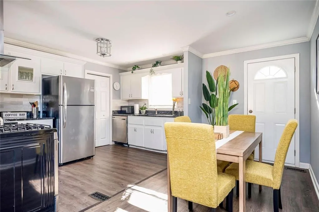 Kitchen featuring white cabinetry, black appliances, crown molding, decorative backsplash, and dark countertops