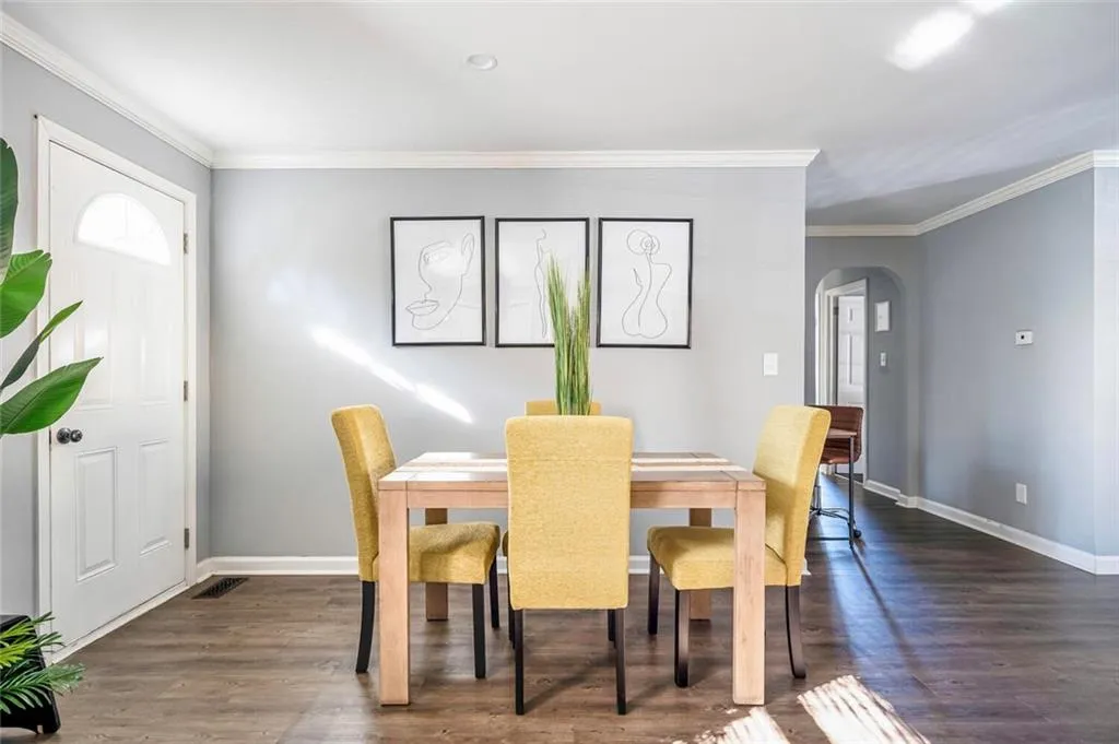 Dining space with arched walkways, crown molding, and dark wood-style flooring
