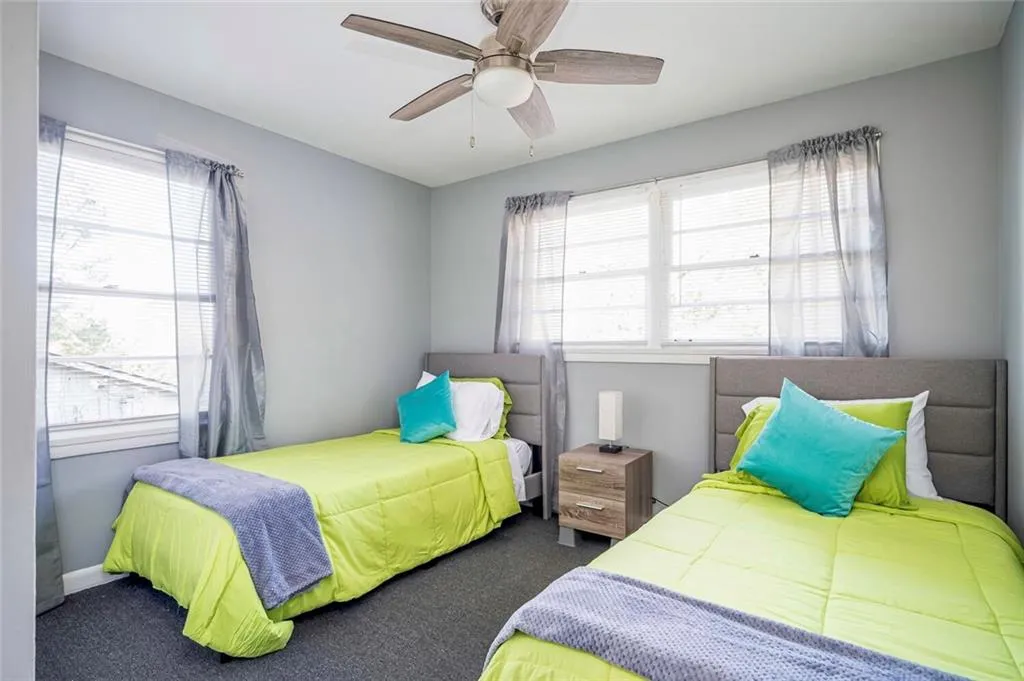 Bedroom featuring multiple windows, carpet floors, and ceiling fan