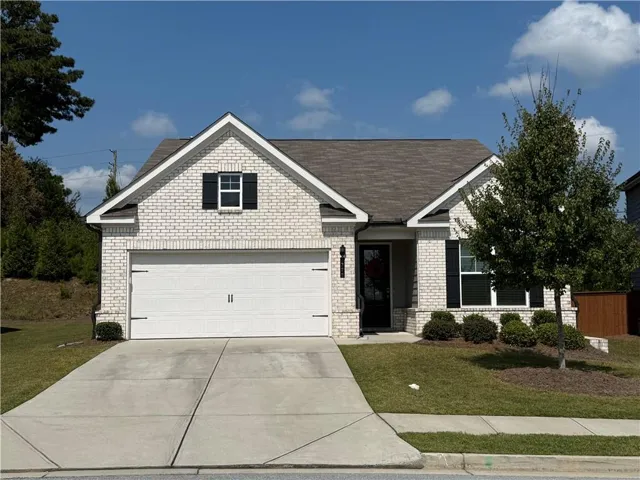 View of front facade with concrete driveway, brick siding, a front lawn, and roof with shingles