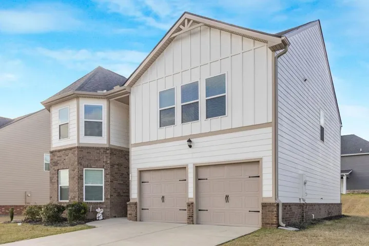 View of front facade featuring board and batten siding, an attached garage, concrete driveway, and a front yard