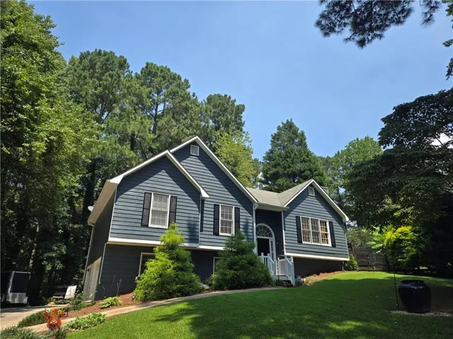 Split-level residence featuring siding, white trim, and a prominent arched entryway