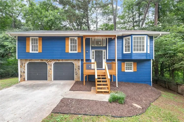 Split-level residence featuring blue siding, stone facade accents, and a two-car garage