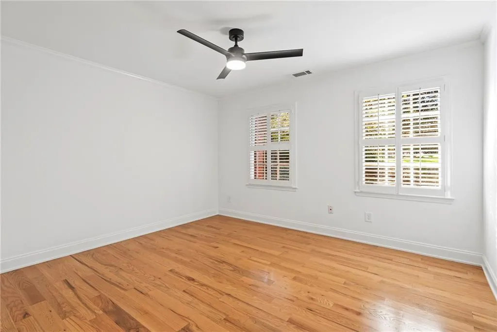Empty room featuring crown molding, light hardwood / wood-style flooring, and ceiling fan