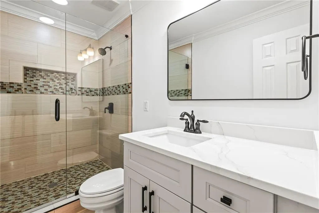 Bathroom with ornamental molding, vanity, a shower with door, wood-type flooring, and toilet