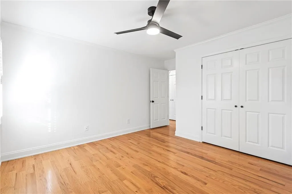 Empty bedroom with ceiling fan, a closet, crown molding, and light hardwood / wood-style flooring