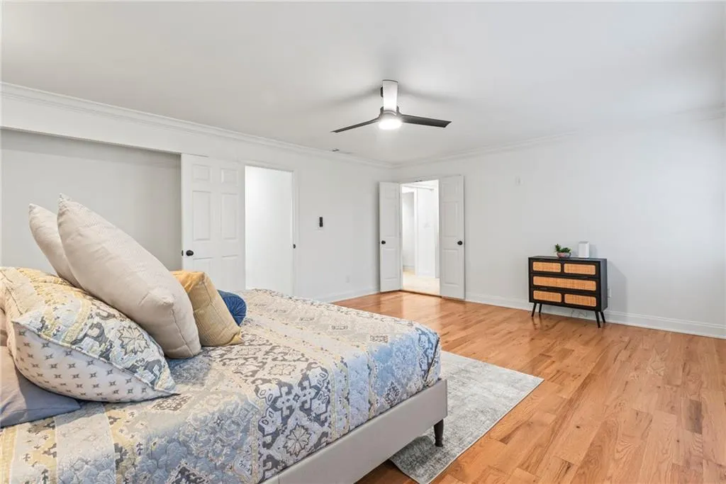 Bedroom featuring ceiling fan, wood-type flooring, and ornamental molding