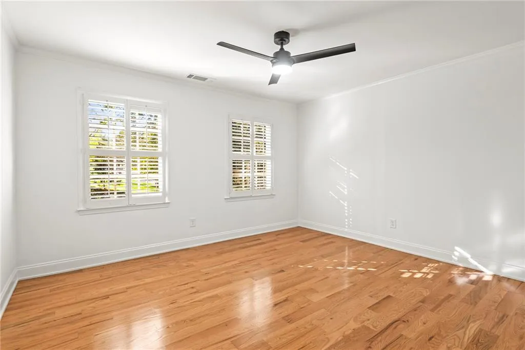 Empty room with ceiling fan, ornamental molding, and light hardwood / wood-style flooring