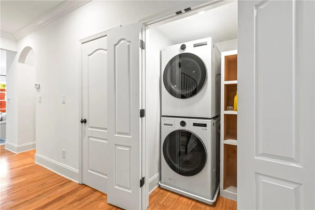 Washroom featuring light hardwood / wood-style flooring, stacked washing maching and dryer, and ornamental molding