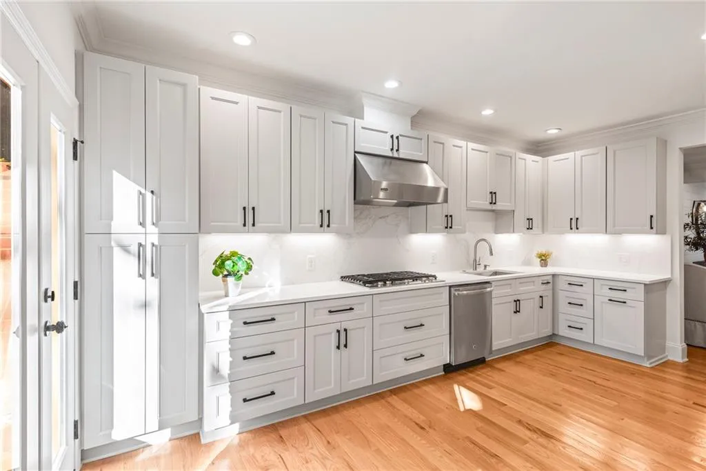 Kitchen featuring sink, light hardwood / wood-style flooring, decorative backsplash, appliances with stainless steel finishes, and ornamental molding