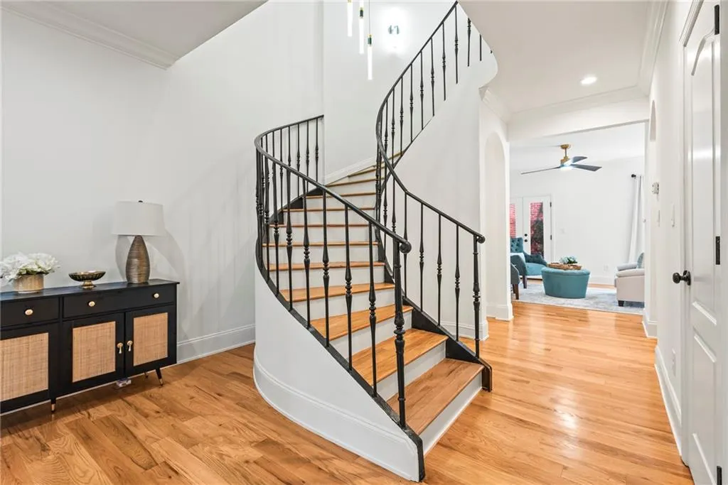 Staircase featuring ceiling fan, wood-type flooring, and crown molding