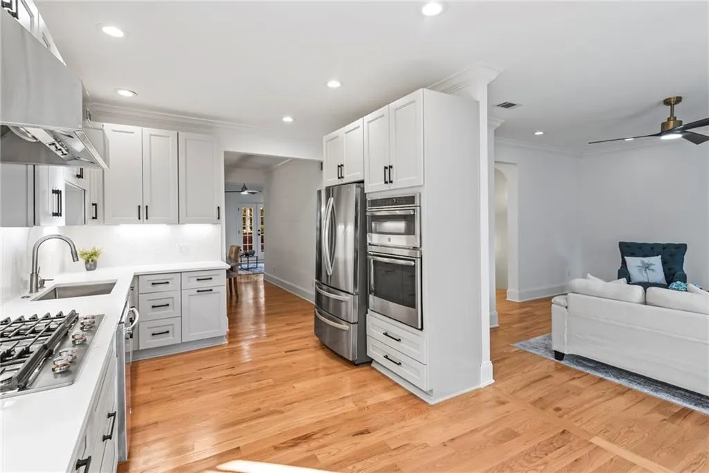 Kitchen with white cabinets, sink, light wood-type flooring, appliances with stainless steel finishes, and extractor fan