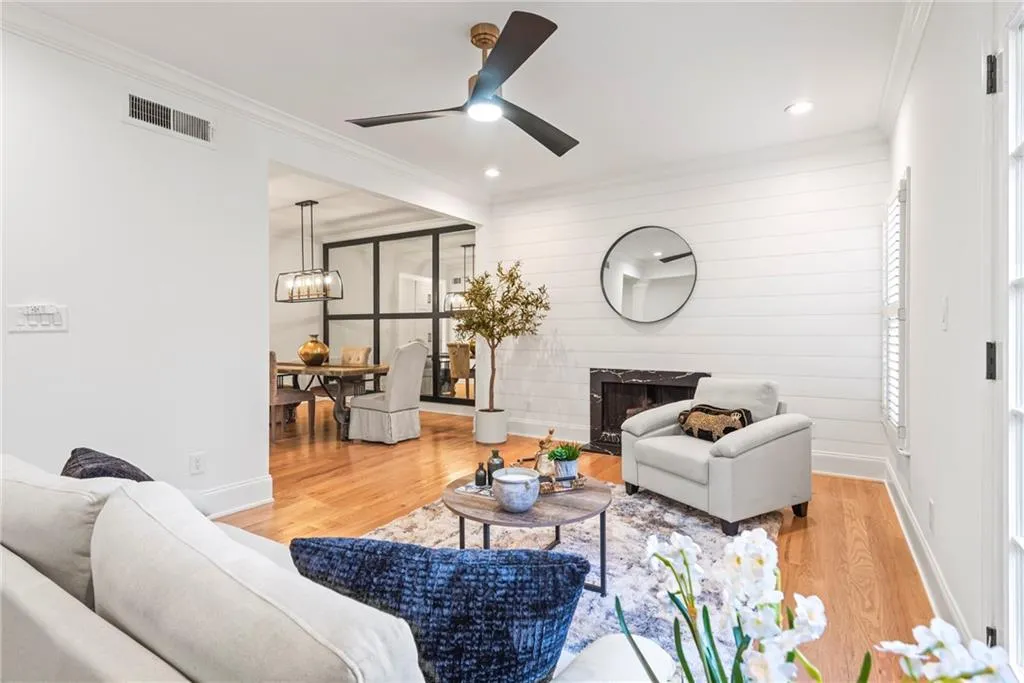 Living room featuring hardwood / wood-style floors, ceiling fan with notable chandelier, a wealth of natural light, and ornamental molding