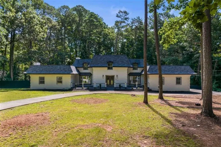 Stately residence featuring a light-colored exterior, dark shingle roof, bay windows, and a paved walkway