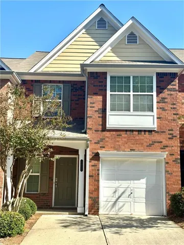 Brick exterior with yellow siding accents, gabled rooflines, and an integrated garage