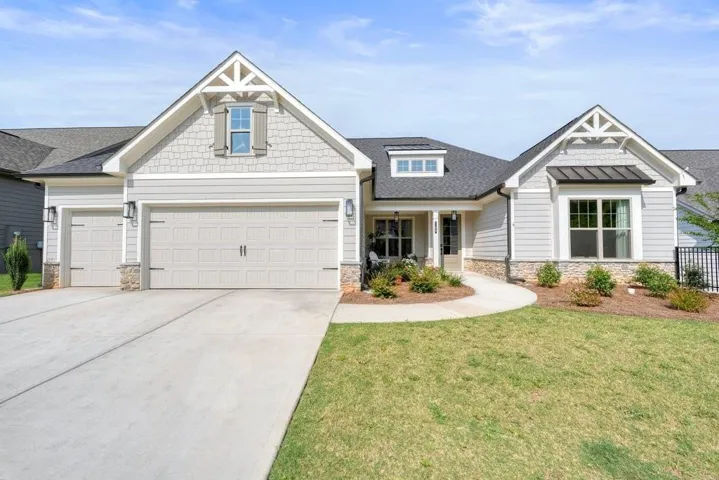 Contemporary ranch-style home featuring a two-car garage, stone veneer accents, and a covered front porch