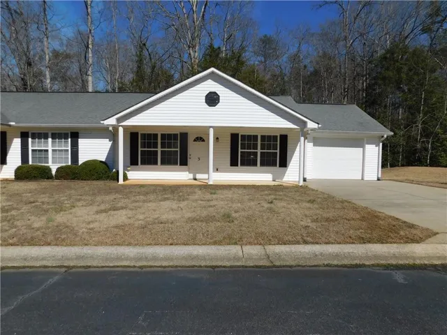 White siding exterior with a covered front porch, attached garage, and asphalt shingle roof