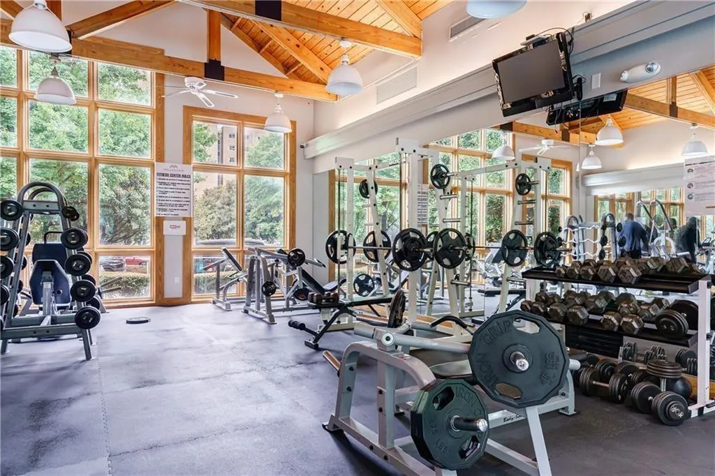 Fitness center with exposed wood beam ceiling, expansive window walls, recessed lighting, and extensive gym equipment