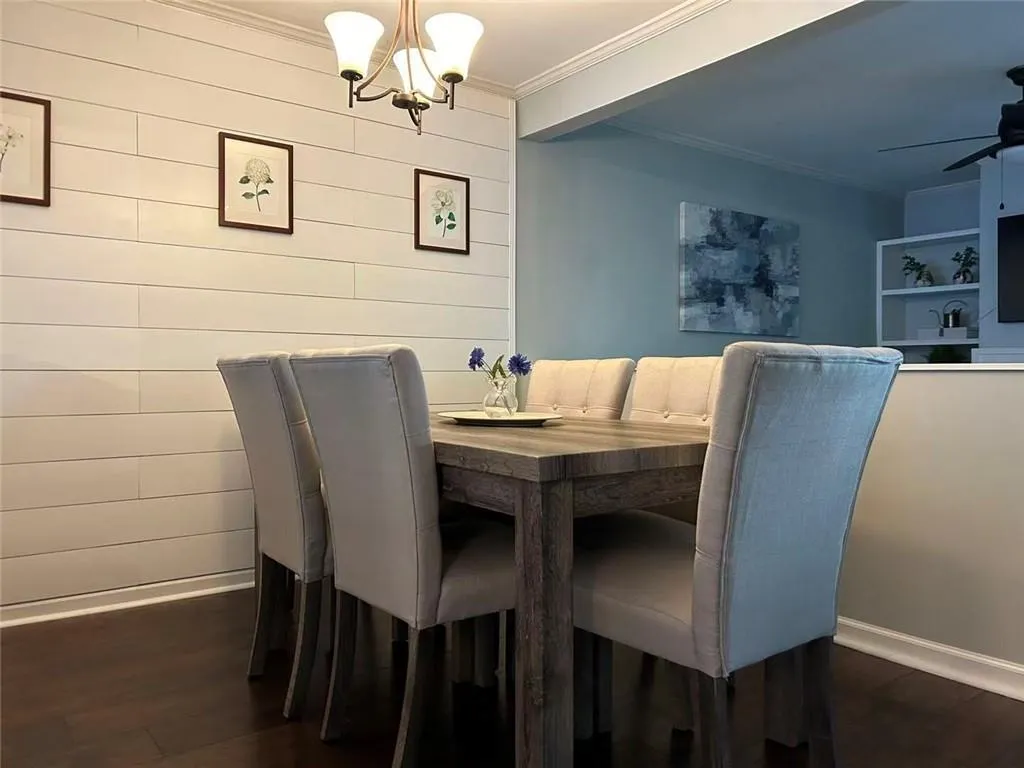 Shiplap accent wall with a three-light chandelier and dark wood-finish flooring