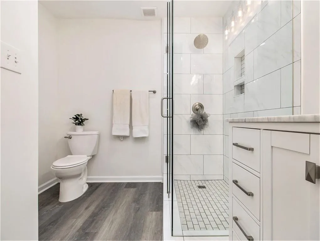 Glass-enclosed shower with subway tile surround, recessed shower niche, and a rain showerhead