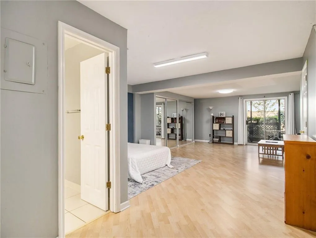 Light wood-finish flooring, sliding glass door leading to exterior, mirrored closet doors, recessed ceiling lighting, and a white interior door