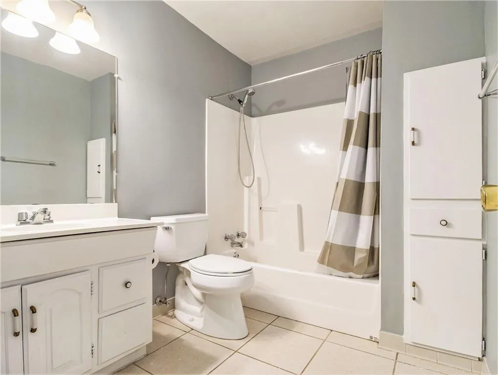 Bathroom featuring a vanity with integrated sink, a commode, a shower-tub combination, and built-in storage cabinetry